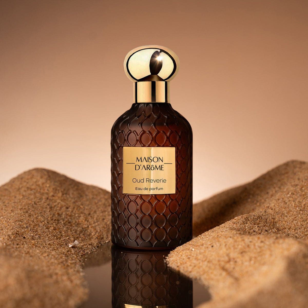 Oud Reverie in amber glass, set in desert sand